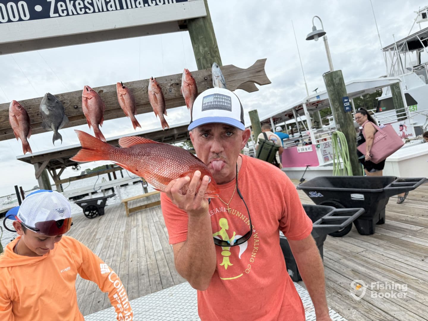 An adult and a child proudly display their catch of Red Snapper at a marina, showcasing a fun family fishing experience.