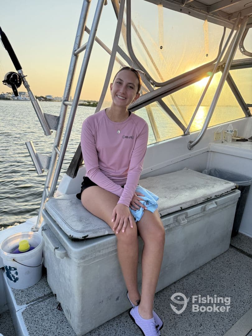 A young angler relaxing inside the boat, showcasing the comfortable seating and scenic waterfront view during a fishing trip.