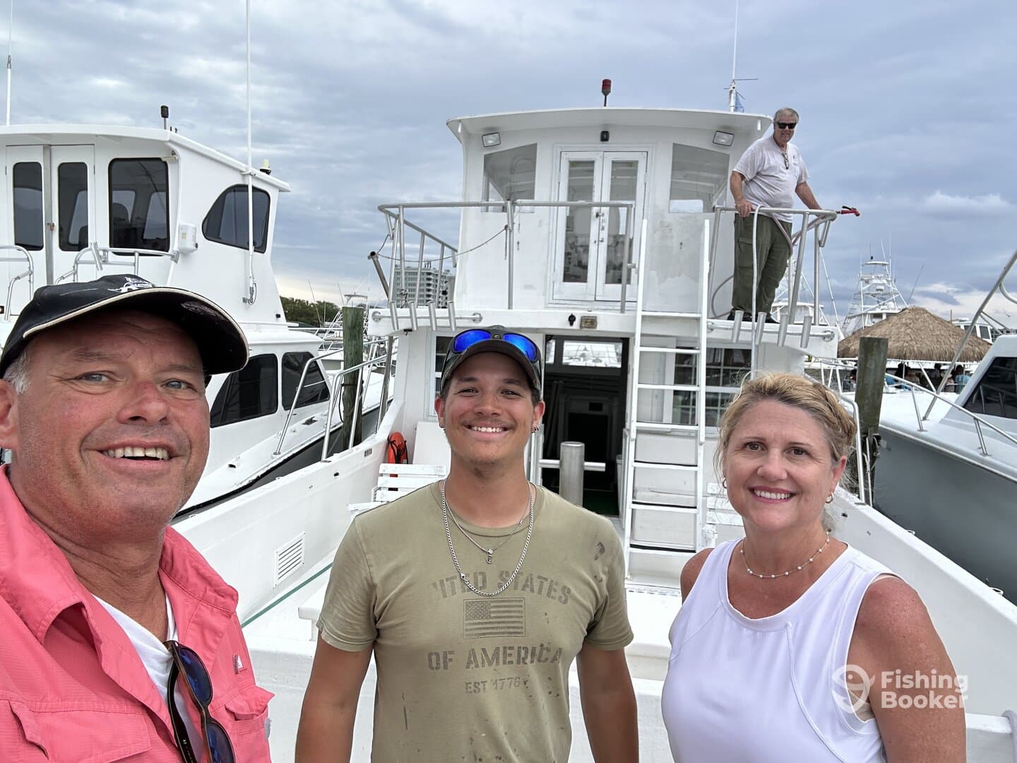A group of three smiling individuals on the deck of a fishing charter boat, showcasing a friendly atmosphere before their fishing adventure.